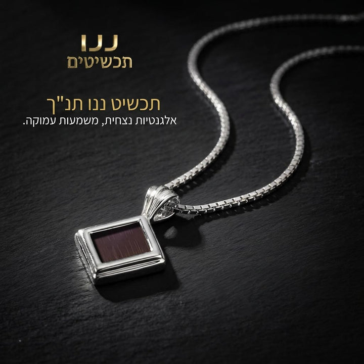 תכשיט לאישה עם תנ"ך, תליון כסוף קטן על משטח שחור מחוספס
